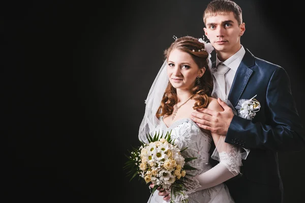 Pengantin pria dan wanita berciuman, berpelukan. foto pernikahan yang diambil di studio dengan latar belakang hitam — Stok Foto