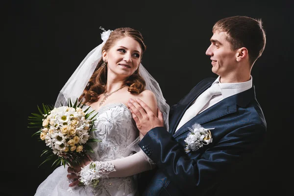 Novia y novio besándose, abrazándose. foto de boda tomada en el estudio sobre fondo negro — Foto de Stock