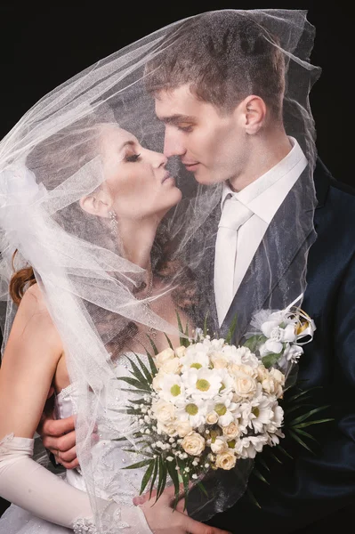 Brudparet kysser Under slöja Holding blombukett i handen. svart bakgrund — Stockfoto