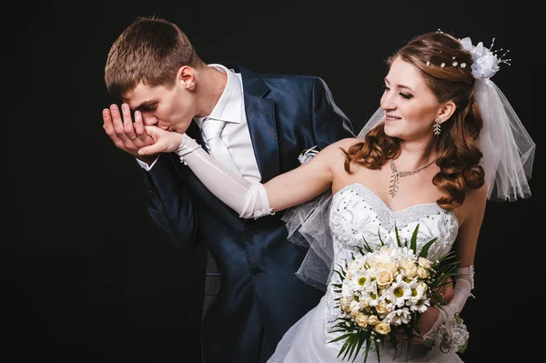 Pengantin pria dan wanita berciuman, berpelukan. foto pernikahan yang diambil di studio dengan latar belakang hitam — Stok Foto