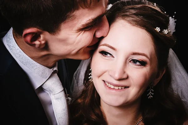 Novia y novio besándose, abrazándose. foto de boda tomada en el estudio sobre fondo negro — Foto de Stock