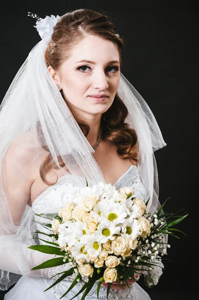 Model busana dengan buket pengantin minum sampanye dan mengenakan gaun pengantin di latar belakang studio hitam — Stok Foto