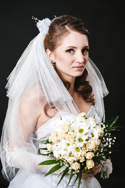 Modelo de moda com buquê de noiva bebendo champanhe e vestindo vestido de noiva no fundo do estúdio preto — Fotografia de Stock