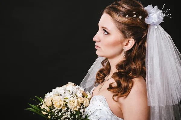 Modella con bouquet da sposa bere champagne e indossare abito da sposa su sfondo nero studio — Foto Stock