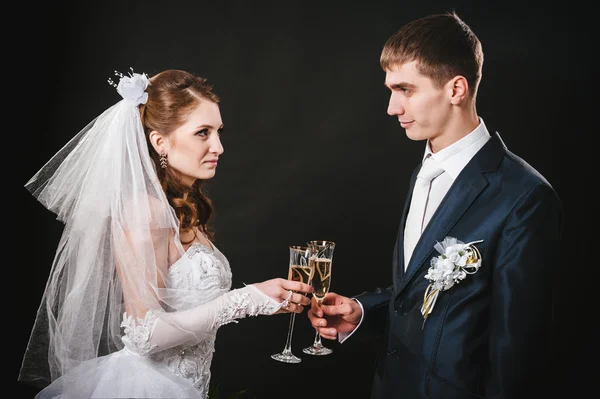 結婚式のカップルはキスをし、シャンパンを飲みます。黒の背景. — ストック写真