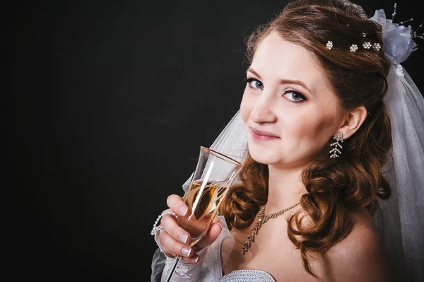 Modella con bouquet da sposa bere champagne e indossare abito da sposa su sfondo nero studio — Foto Stock