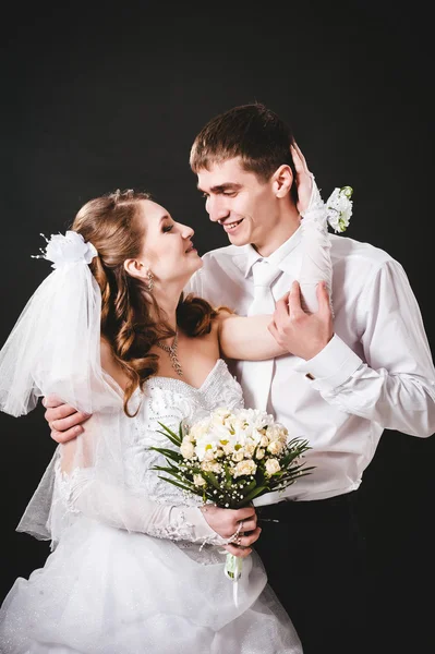 Ženich líbání nevěsty na svatbu. Černé pozadí. — Stock fotografie