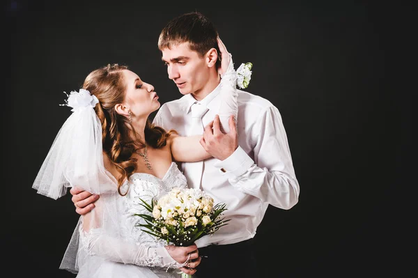 Ženich líbání nevěsty na svatbu. Černé pozadí. — Stock fotografie