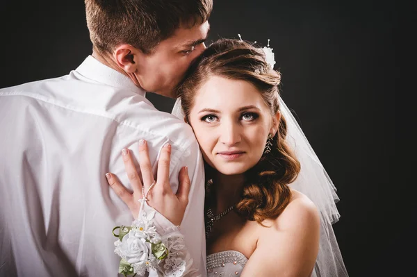 Groom kissing bride on wedding. Black background. — Stock Photo, Image