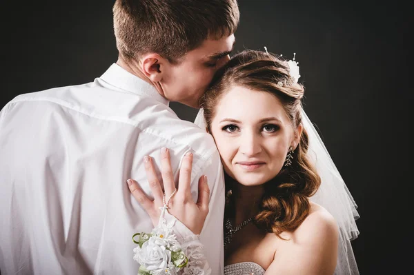 Groom kissing bride on wedding. Black background. — Stock Photo, Image