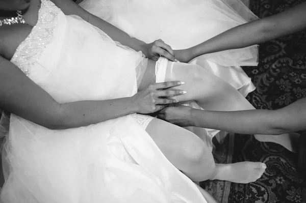 Jarretière sur la jambe de la mariée, mariée sexy mince en robe de luxe nuptiale montrant sa jarretière en soie avec ruban doré. femme ont la préparation finale pour la cérémonie de mariage. Moments de mariage — Photo