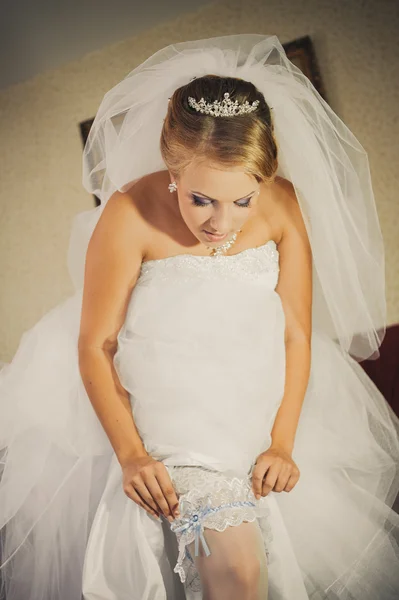 ♥ 高級でスリムなセクシーな花嫁花嫁の脚にガーター ドレス ゴールデン リボンと彼女のシルクのガーターを示します。女性の結婚式のための最終的な準備があります。結婚式の日の瞬間 — ストック写真