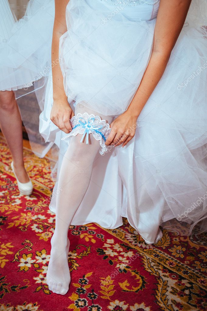 Garter on leg of bride, slim sexy bride in bridal luxury dress showing