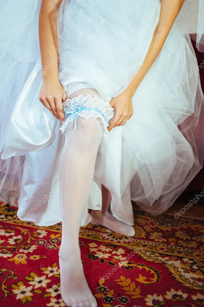 Garter on leg of bride, slim sexy bride in bridal luxury dress