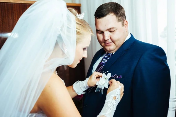 Brudar hand sätta boutonniere blomman på brudgummen — Stockfoto