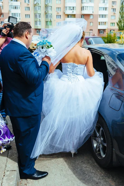 Happy groom helping his bride out of the wedding car. — Stock Photo, Image