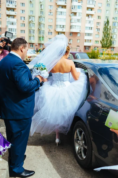 Happy groom helping his bride out of the wedding car. — Stock Photo, Image