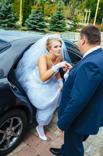 Šťastný ženich pomáhá jeho nevěsta ze svatební auta. — Stock fotografie