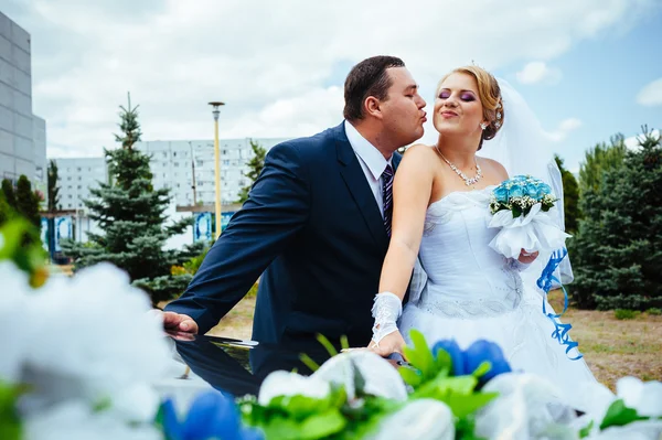 Gelukkige bruidegom zijn bruid uit de bruiloft auto helpen. — Stockfoto