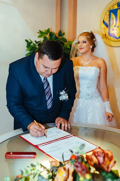 Une cérémonie de mariage. Bureau du greffe. Un couple nouvellement marié signe le document de mariage.Jeune couple signant les documents de mariage — Photo