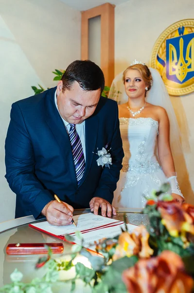 De ceremonie van het huwelijk. Kadaster. Een nieuw getrouwde paar ondertekent het huwelijk document. Jong koppel bruiloft documenten ondertekenen — Stockfoto