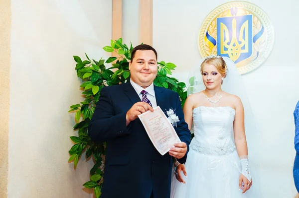 Az esküvői szertartás. Anyakönyvi hivatal. Az újonnan házas pár jelek a házasság dokumentum. Fiatal pár esküvői dokumentumok aláírásakor — Stock Fotó