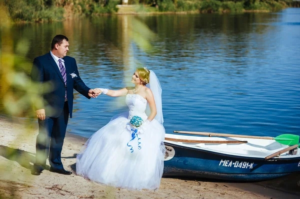 Liefdevolle bruidspaar, wandelen en kussen in de buurt van water — Stockfoto