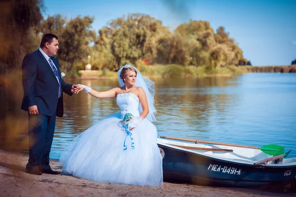 Liefdevolle bruidspaar, wandelen en kussen in de buurt van water — Stockfoto