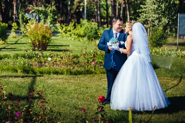 Nevěsty a ženicha na svatební den chůze venku na jarní přírody. Novomanželé šťastní novomanželé objímat v parku. — Stock fotografie