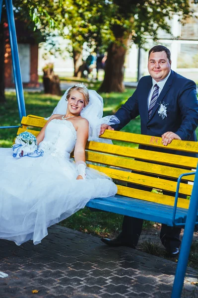 Happy bride and groom swinging on a swing in the park — Stock Photo, Image