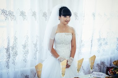 parlak makyaj ve saç modeli ile giysi güzel gelin beyaz gelinlik içinde hazırlanıyor. Damat için bekleyen mutlu seksi kız. Gelin elbiseli romantik Bayan var düğün için son hazırlık ve sunuş.