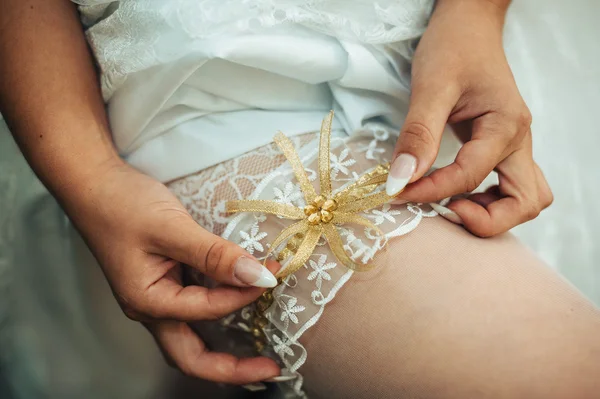 Vestidos de noiva liga na perna. A noiva veste meias em pernas. Noiva colocando uma liga de casamento em sua perna — Fotografia de Stock