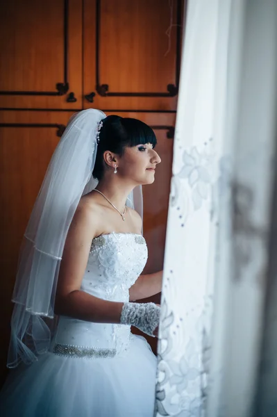 beautiful bride getting ready in white wedding dress with hairstyle and bright makeup. Happy sexy girl waiting for groom. Romantic lady in bridal dress have final preparation for wedding.