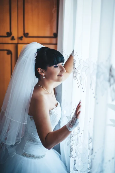 Beautiful bride getting ready in white wedding dress with hairstyle and bright makeup. Happy sexy girl waiting for groom. Romantic lady in bridal dress have final preparation for wedding. — Stock Photo, Image