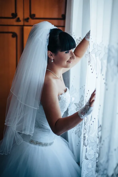 Schöne Braut immer bereit in weißem Hochzeitskleid mit Frisur und hellem Make-up. glücklich sexy Mädchen wartet auf Bräutigam. Romantikerin im Brautkleid hat letzte Vorbereitungen für Hochzeit. — Stockfoto