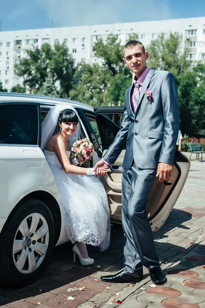 Šťastný ženich pomáhá jeho nevěsta ze svatební auta — Stock fotografie