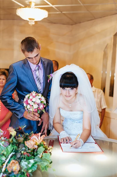 Cerimonia nuziale. Ufficio di cancelleria. Una coppia appena sposata firma il documento di matrimonio.Giovane coppia firma documenti di nozze . — Foto Stock
