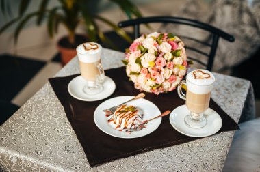 Gelin ve damat elleri. Cappuccino veya kalp şekli ile kahve latte. Gelin ve damat bir fincan kahve latte tarihini iç. Mutlu gelin ve damat bir fincan kahve latte kalp tasarımı ile içmek