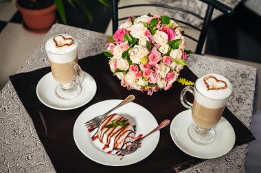 Gelin ve damat elleri. Cappuccino veya kalp şekli ile kahve latte. Gelin ve damat bir fincan kahve latte tarihini iç. Mutlu gelin ve damat bir fincan kahve latte kalp tasarımı ile içmek
