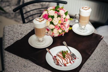 Gelin ve damat elleri. Cappuccino veya kalp şekli ile kahve latte. Gelin ve damat bir fincan kahve latte tarihini iç. Mutlu gelin ve damat bir fincan kahve latte kalp tasarımı ile içmek