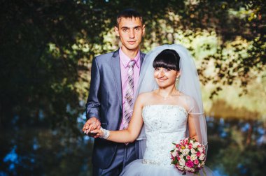 Gelin ve damat, düğün günü açık havada yürüyüş Doğa bahar. mutlu yeni evli kadın ve erkek yeşil park kucaklayan gelin çift. sevgi dolu evlilik çift açık