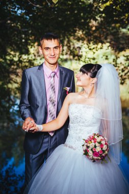 Gelin ve damat, düğün günü açık havada yürüyüş Doğa bahar. mutlu yeni evli kadın ve erkek yeşil park kucaklayan gelin çift. sevgi dolu evlilik çift açık