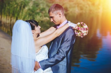 Evli çift nehir kumsalda öpüşme. Gelin Damat çift evlilik açık rivershore üzerinde yürüme