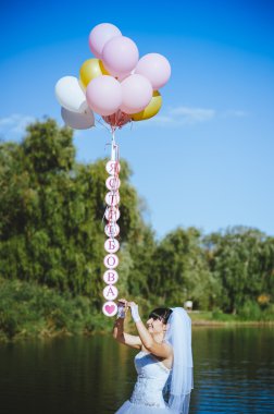 Büyük renkli lateks balonlar sahil üzerinde mutlu genç kızla. Güzellik romantik kız açık havada. Mavi gökyüzü arka plan üzerinde bir elektrik direği eğleniyor uzun sarı dalgalı saçlı kadın.