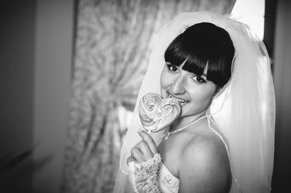 Portrait of a young bride with a heart-shaped candy lollipop — Stock Photo, Image