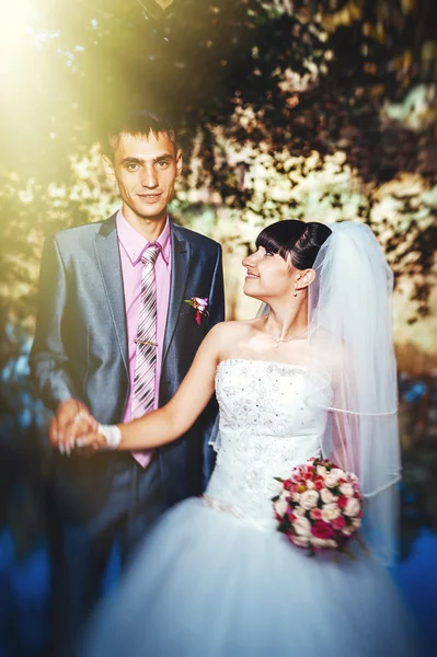 Noiva e noivo no dia do casamento andando ao ar livre na natureza de primavera. Casal nupcial, mulher recém-casada feliz e homem abraçando no parque verde. Casal de amor ao ar livre — Fotografia de Stock