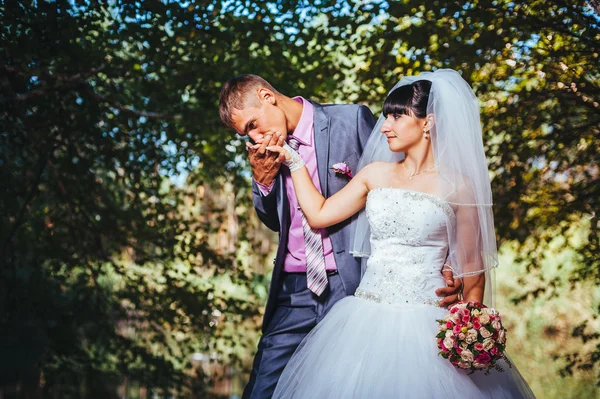 Novia y novio en el día de la boda caminando al aire libre en la naturaleza de primavera. Pareja nupcial, feliz mujer recién casada y hombre abrazándose en el parque verde. Amar pareja de boda al aire libre —  Fotos de Stock