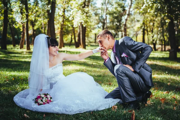 Novia y novio en el día de la boda caminando al aire libre en la naturaleza de primavera. Pareja nupcial, feliz mujer recién casada y hombre abrazándose en el parque verde. Amar pareja de boda al aire libre — Foto de Stock