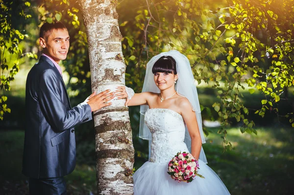 Novia y novio en el día de la boda caminando al aire libre en la naturaleza de primavera. Pareja nupcial, feliz mujer recién casada y hombre abrazándose en el parque verde. Amar pareja de boda al aire libre — Foto de Stock