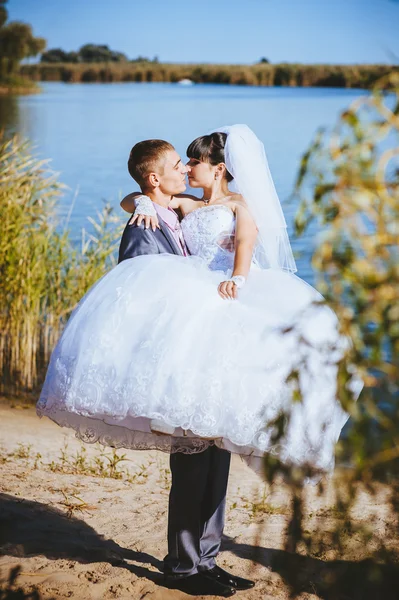 Novia y novio en el día de la boda caminando al aire libre en la naturaleza de primavera. Pareja nupcial, feliz mujer recién casada y hombre abrazándose en el parque verde. Amar pareja de boda al aire libre — Foto de Stock